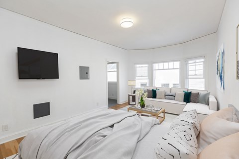 A bedroom with a bed, a couch, and a television on the wall.
