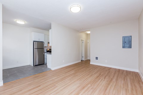 A kitchen with a refrigerator and a wooden floor.