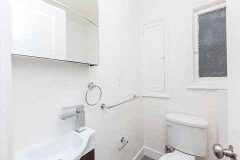 A white toilet sits next to a white sink in a small bathroom.