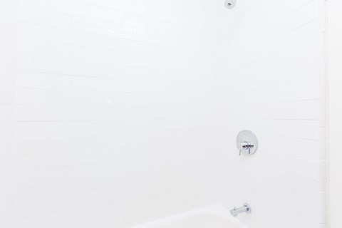 A white bathroom with a shower and a faucet.