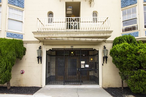 A white building with a black gate and a balcony.
