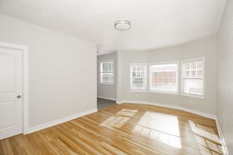 an empty living room with a hard wood floor and windows