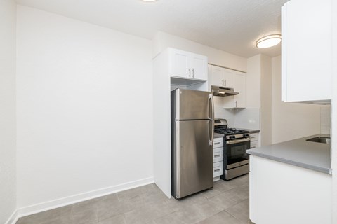A kitchen with a stainless steel refrigerator and a white counter.