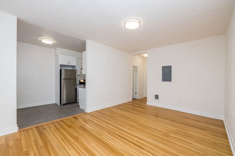 A kitchen with a refrigerator and a wooden floor.