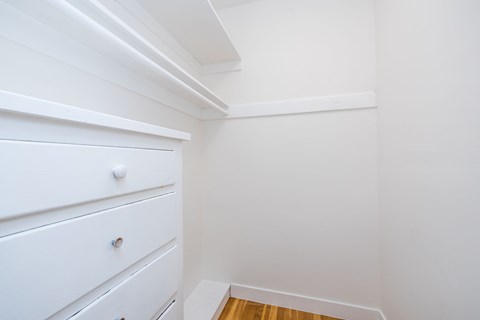 A white drawer is in the corner of a room.