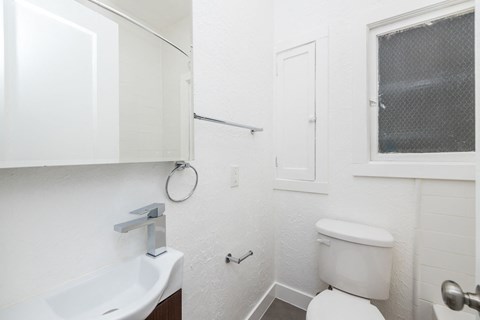 A white toilet sits next to a white sink in a small bathroom.