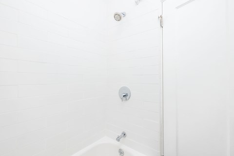 A white bathroom with a shower head and a faucet.