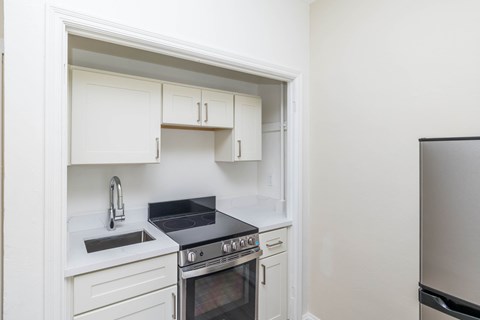 A kitchen with white cabinets and a black stove top.