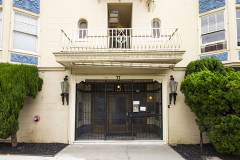 A white building with a black gate and a balcony.