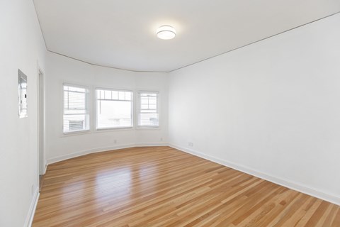 A room with wooden flooring and white walls.