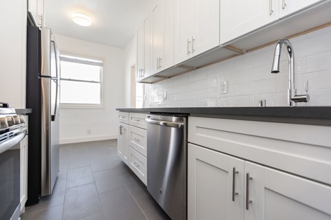 A modern kitchen with white cabinets and stainless steel appliances.