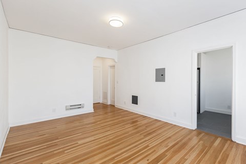 A room with wooden flooring and white walls.