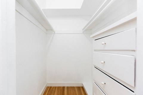 A white cabinet with three drawers is in a room with white walls.