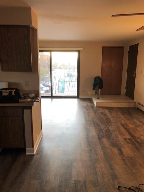 an empty living room with wooden floors and a door to a balcony