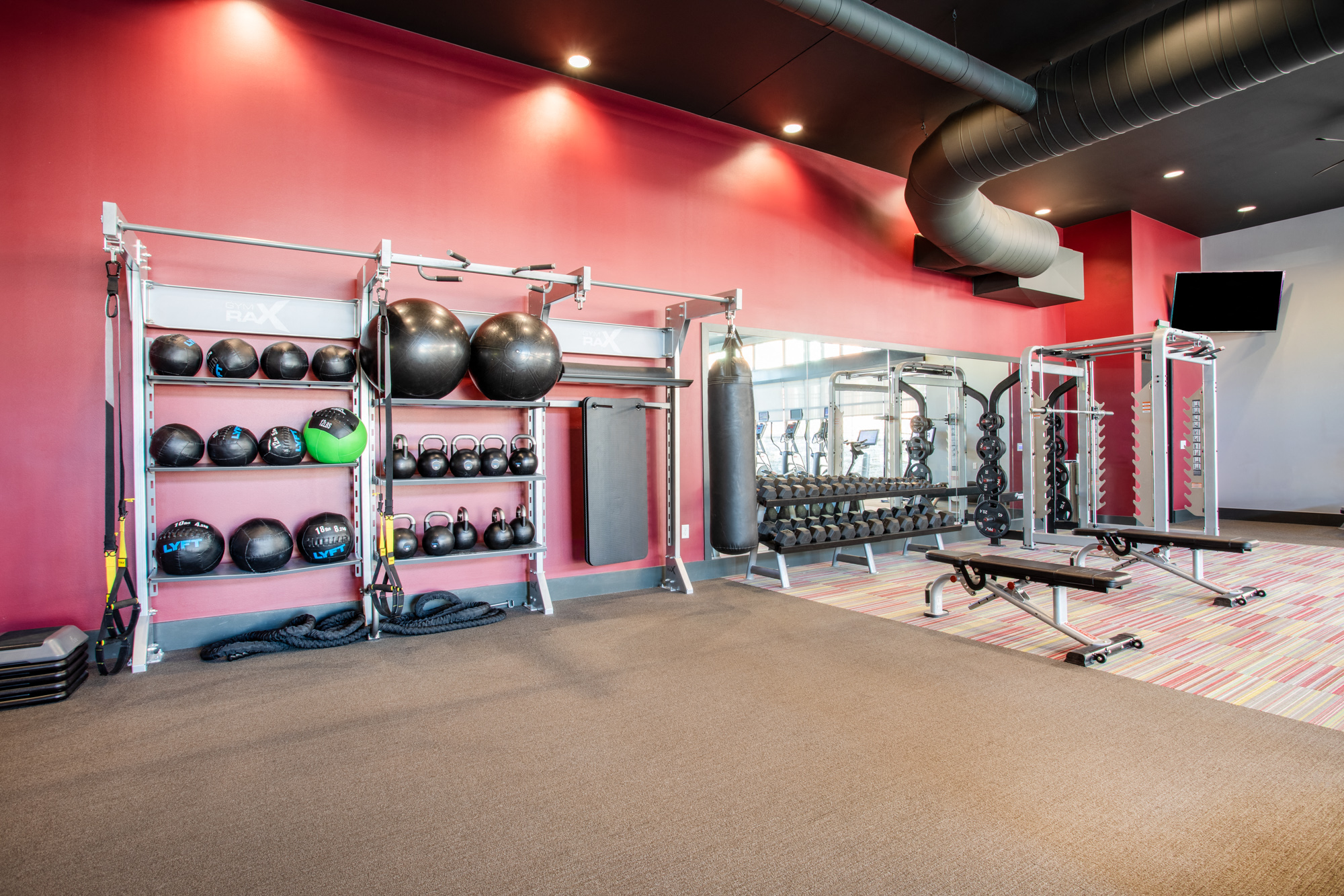 a gym with weights and other equipment and a red wall