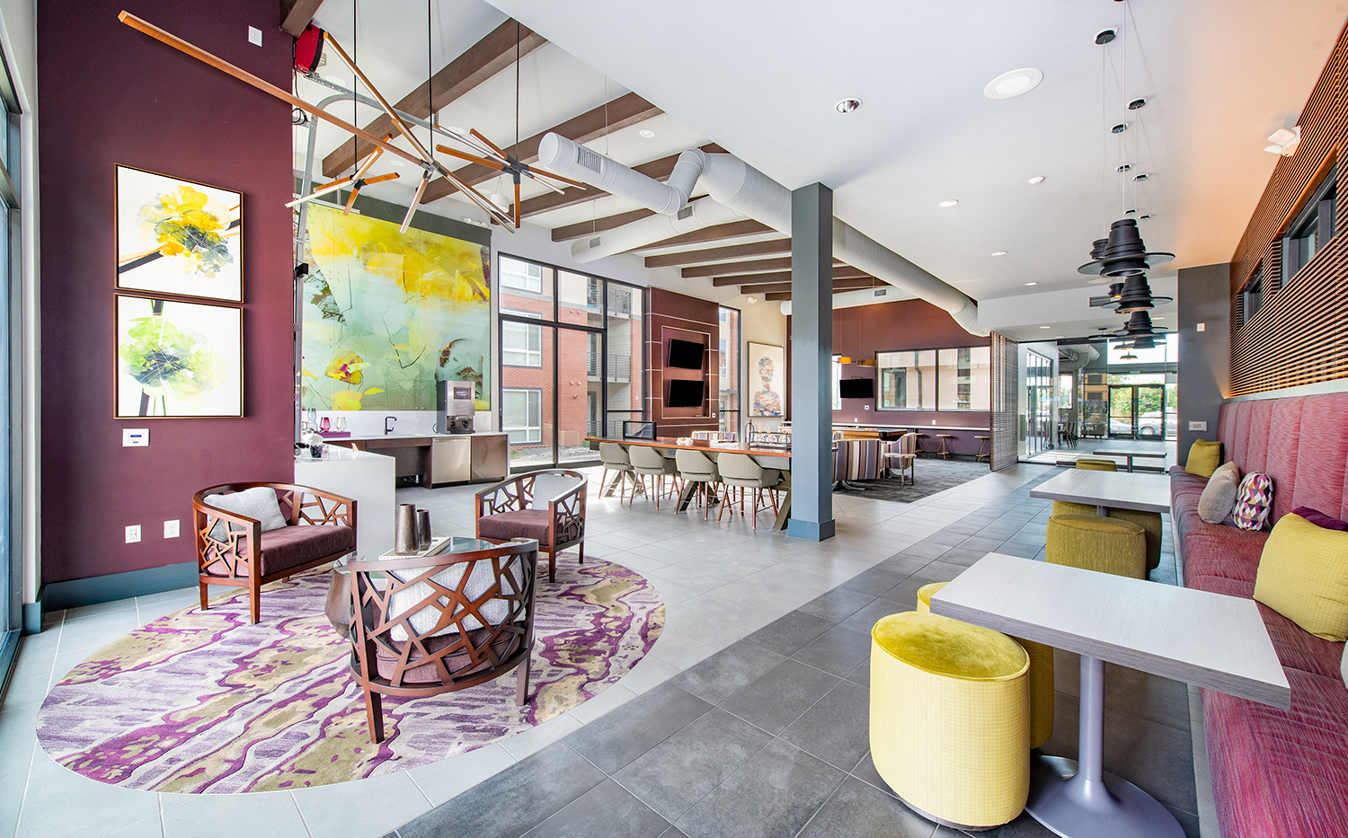 a large lobby with tables and chairs and a large painting on the wall