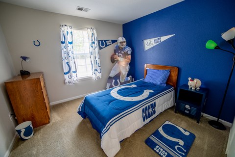 a boy bedroom with a bed and a blue wall and a baseball player