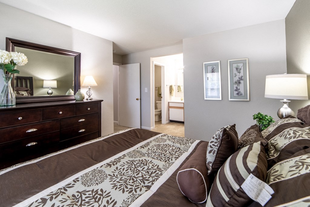 a bedroom with a bed and a dresser and a mirror