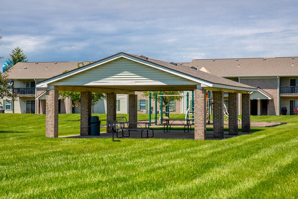 a pavilion with a picnic table in front of a building
