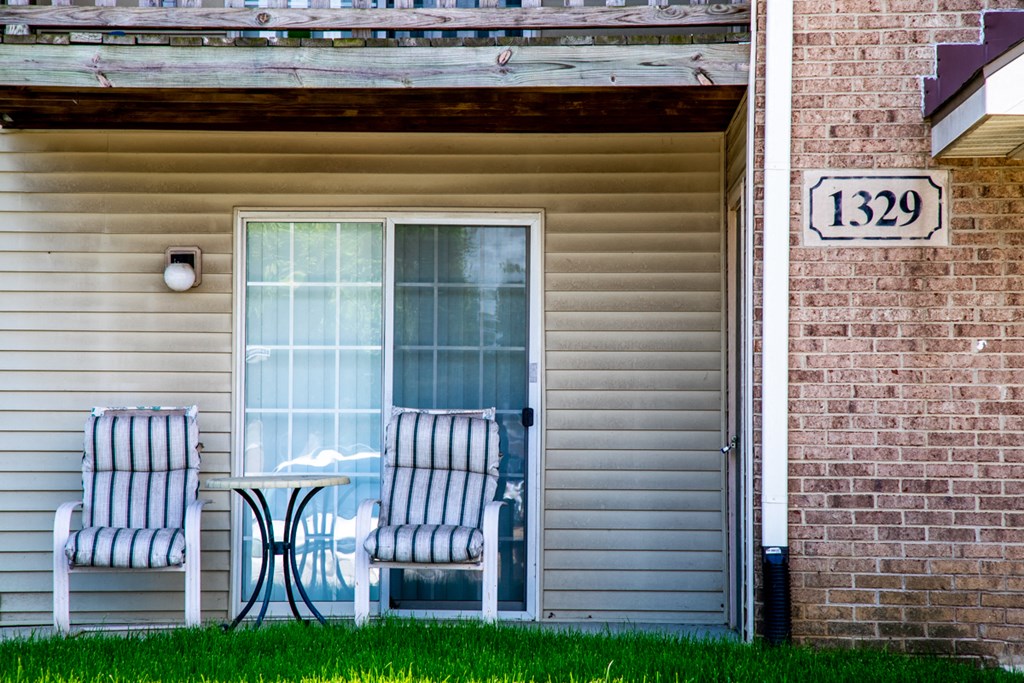 the front porch of a house with two chairs and a table