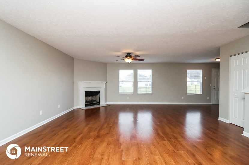the living room with wood floors and a fireplace