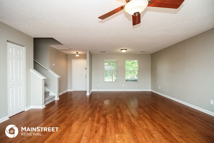 an empty living room with wood floors and a ceiling fan