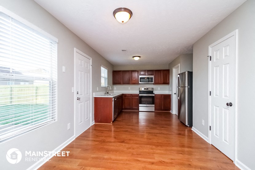 an empty kitchen with wood flooring and a large window