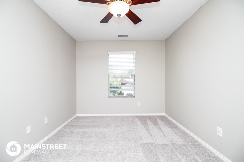 an empty room with a ceiling fan and a window