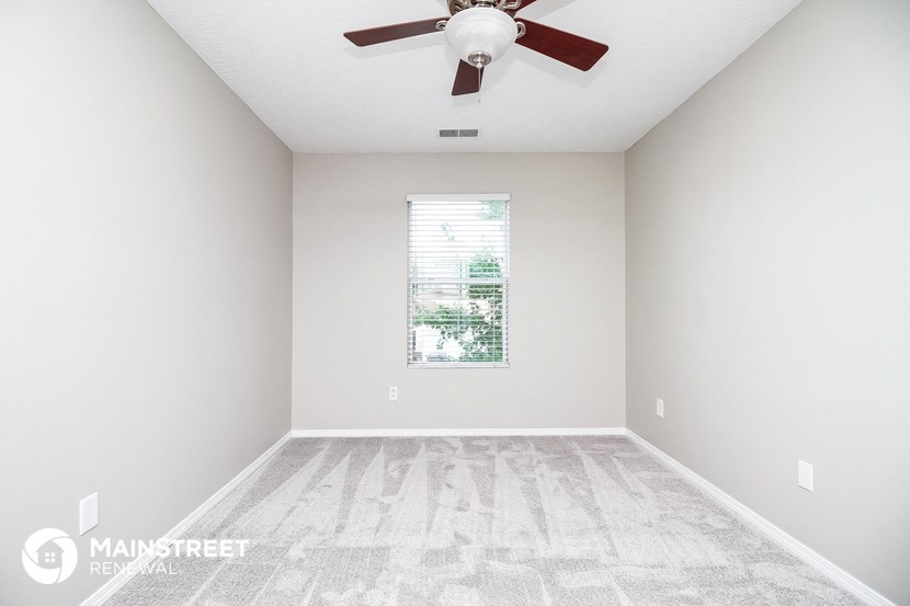 an empty room with a ceiling fan and a window