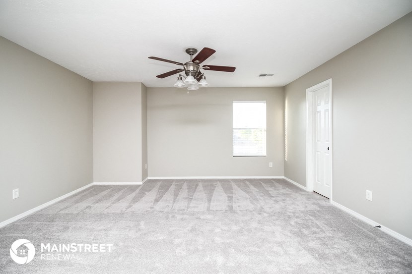 the spacious living room with carpet and ceiling fan