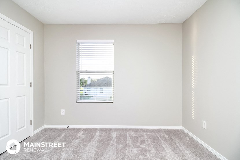 the spacious living room with carpeting and a window