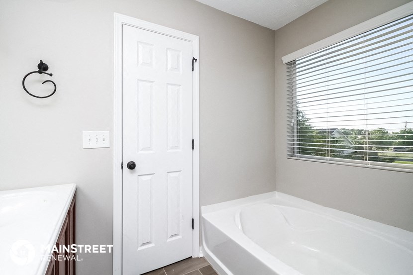 a bathroom with a tub and a sink and a window