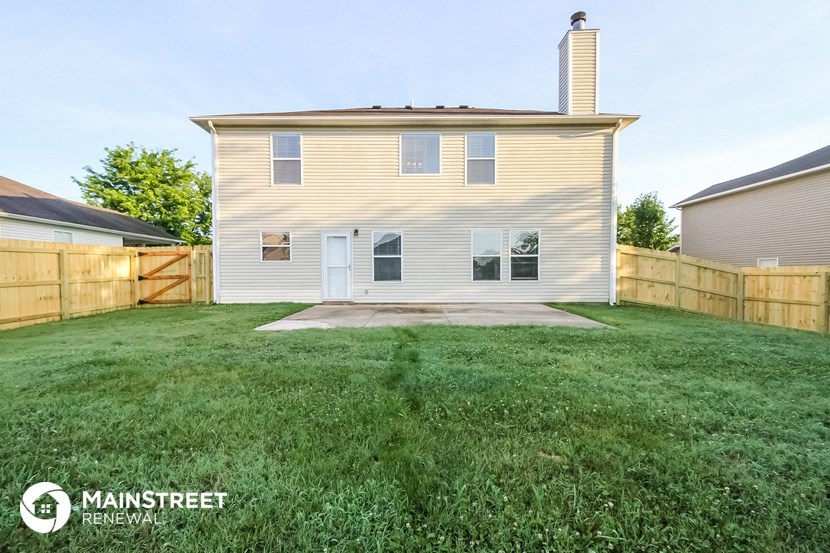 the back of a house with a yard and a fence