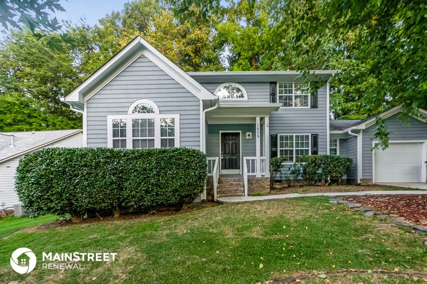 a blue house with a lawn and hedges