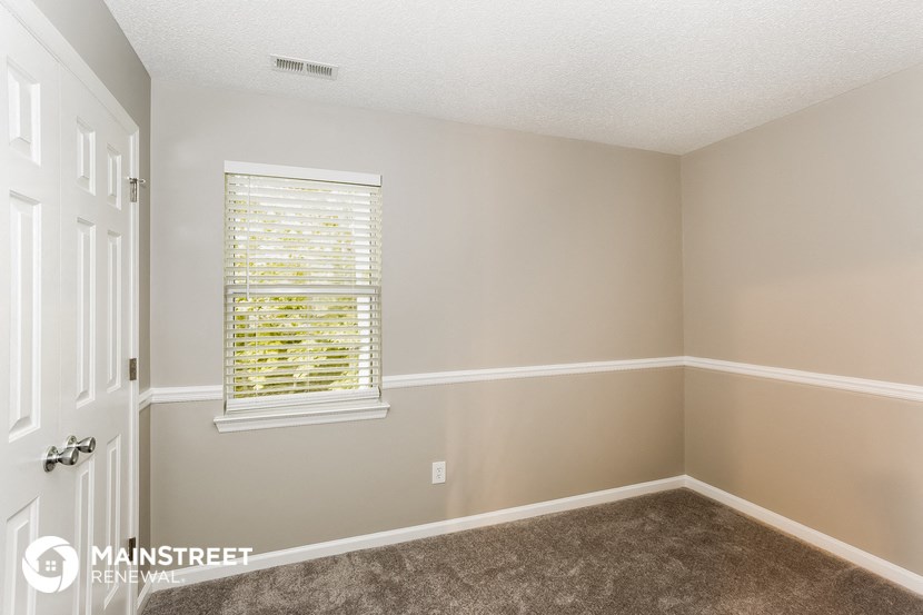 the bedroom of a house with a window and carpet