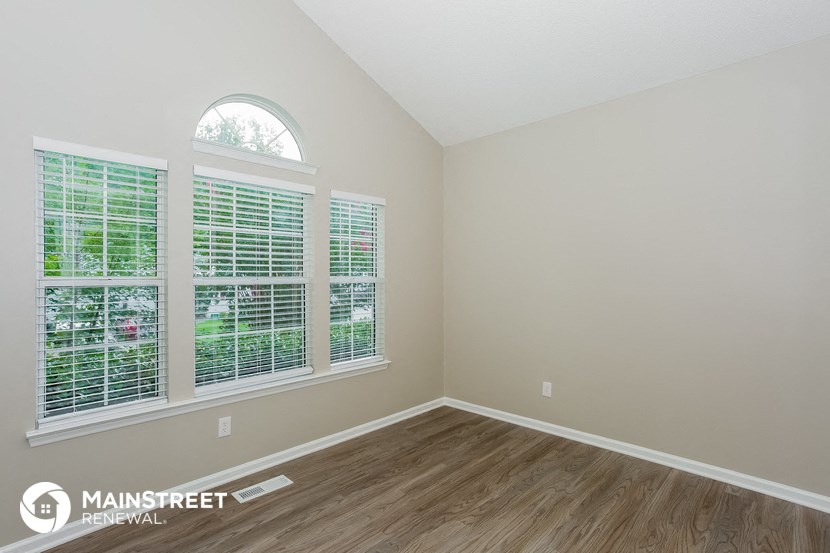 the living room of a rental house with wood flooring and large windows