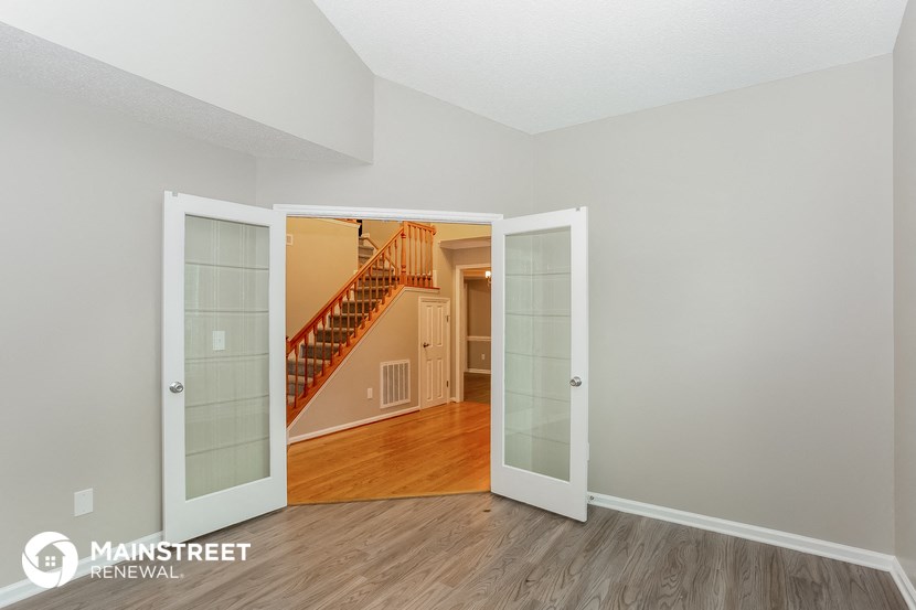 the living room of an apartment with an open door to the hallway