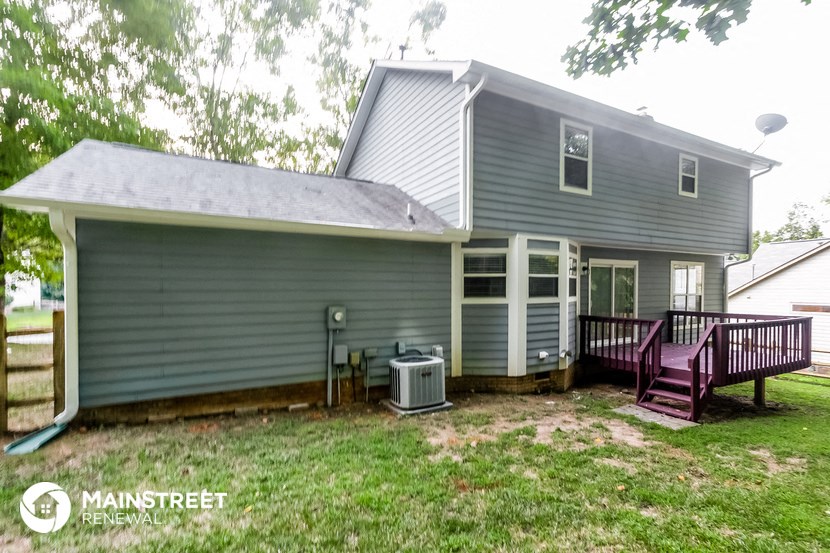 a blue house with a deck and a purple bench
