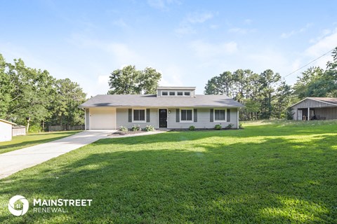 a small white house with a lawn and a driveway