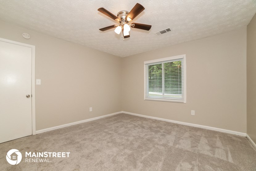the upstairs bedroom has a carpeted floor and a ceiling fan