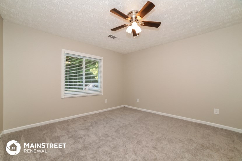 the upstairs bedroom has a ceiling fan and beige carpet