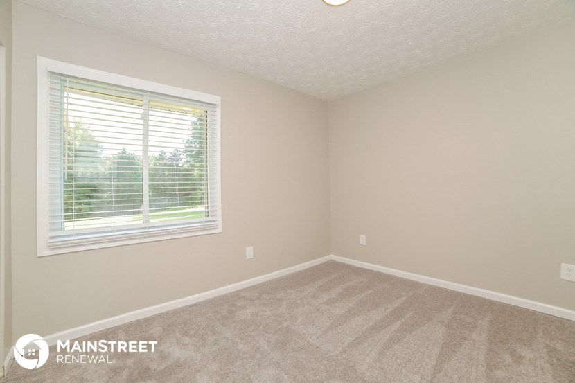 the upstairs bedroom with carpet and a window