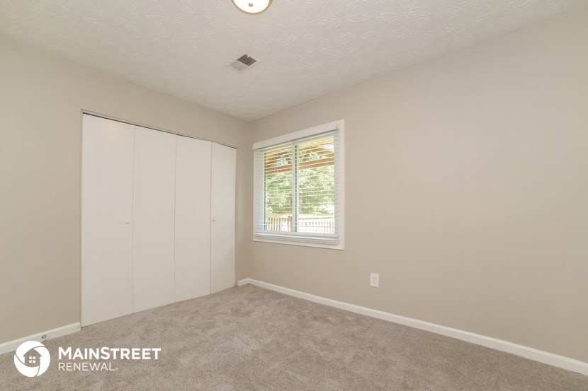 the living room of a house with carpet and a window