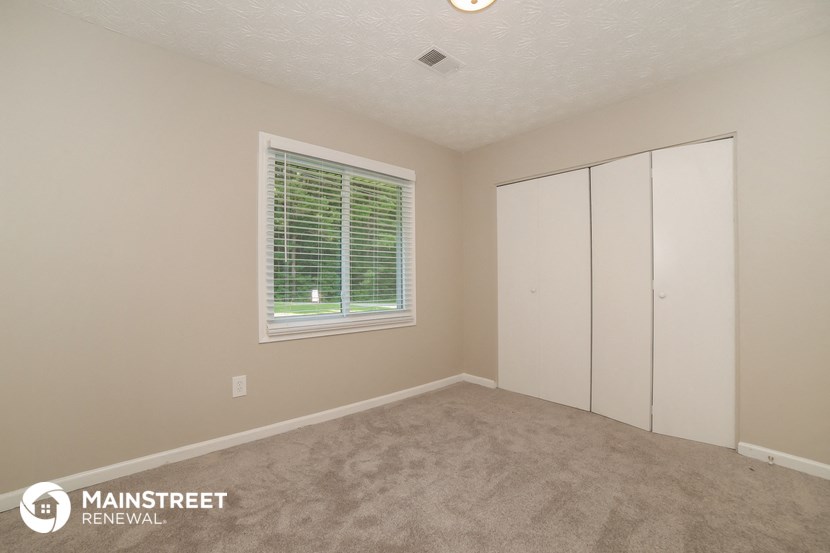 a bedroom with carpet and a large window and white closets