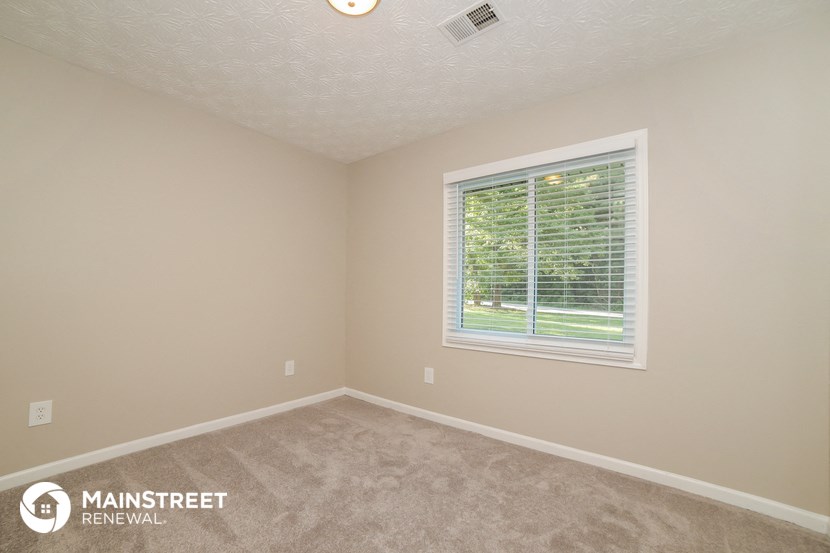 the upstairs bedroom has a large window and carpeted flooring