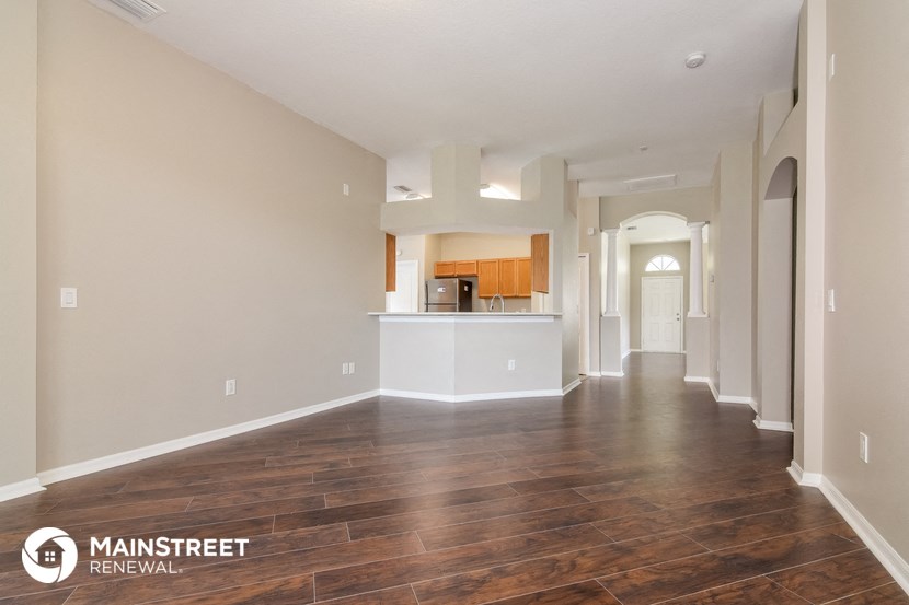 the living room and kitchen of an apartment with wood flooring