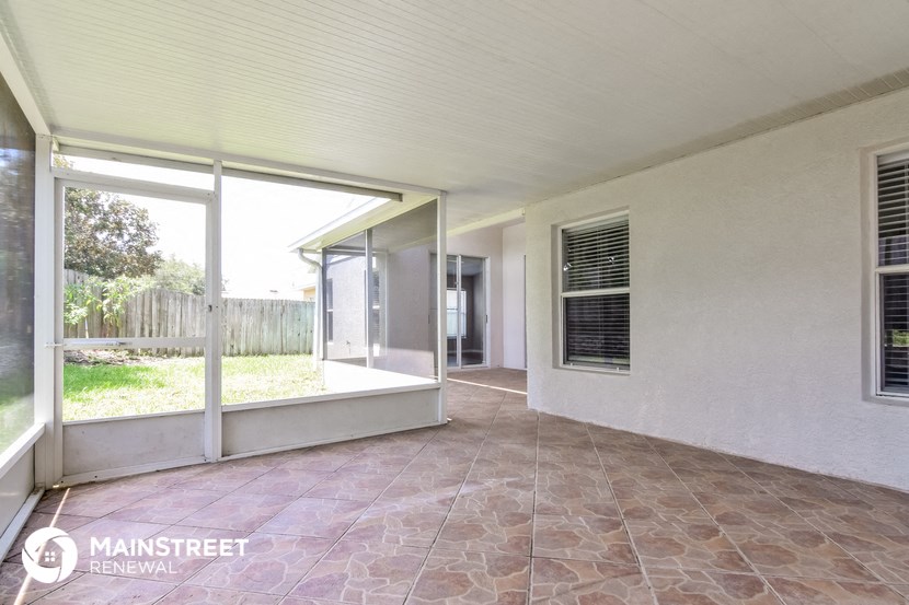 a patio with glass doors and a white house with a porch