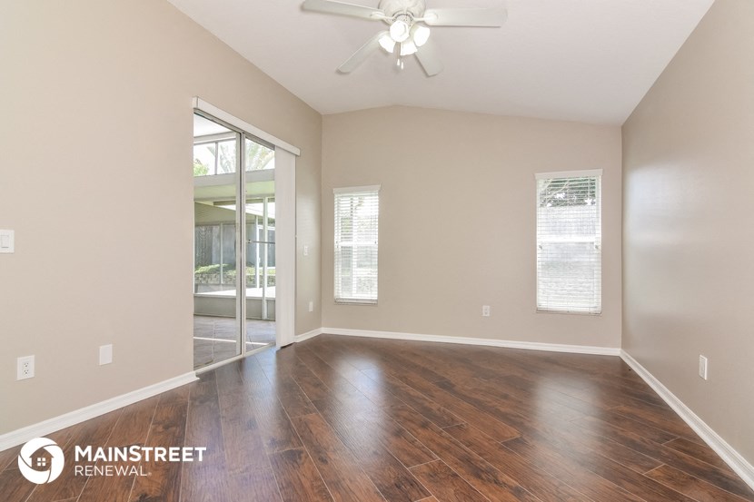 the spacious living room with wood flooring and a ceiling fan