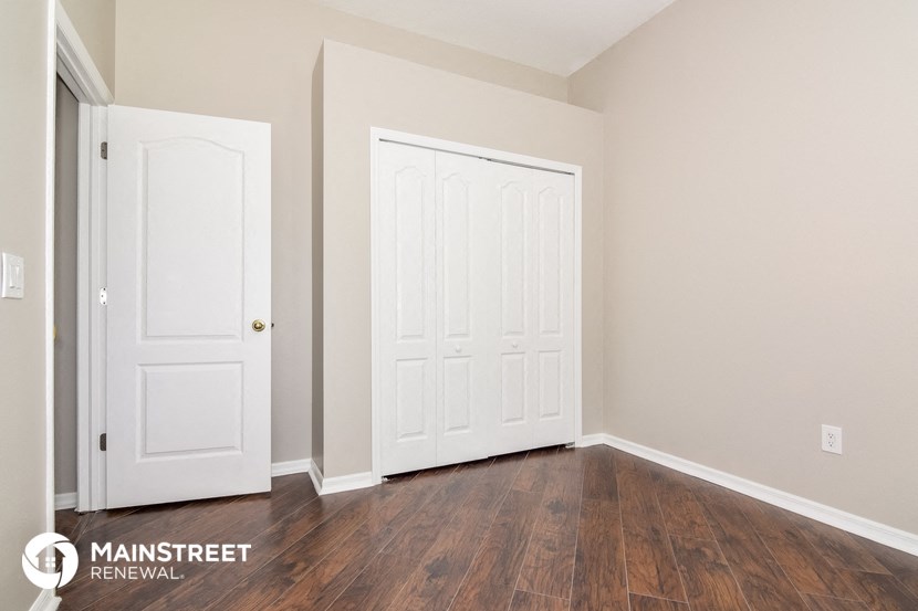 a bedroom with two white doors and a wood floor