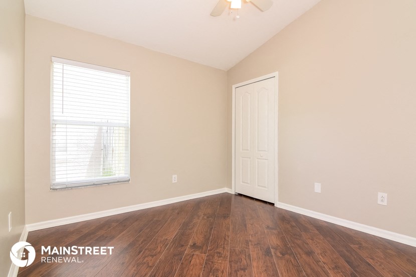the spacious living room with hardwood flooring and a window